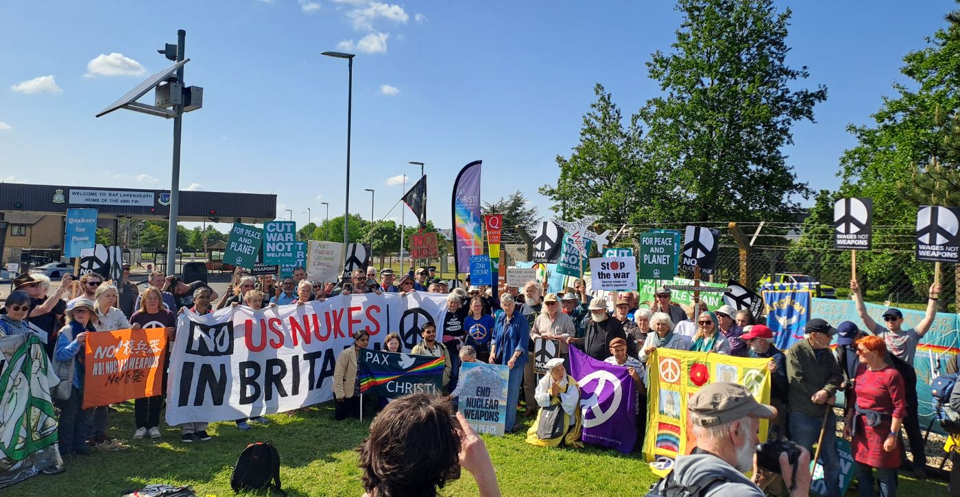 Protesters gathered for group photo outside Lakenheath airbase. Main banner reads 