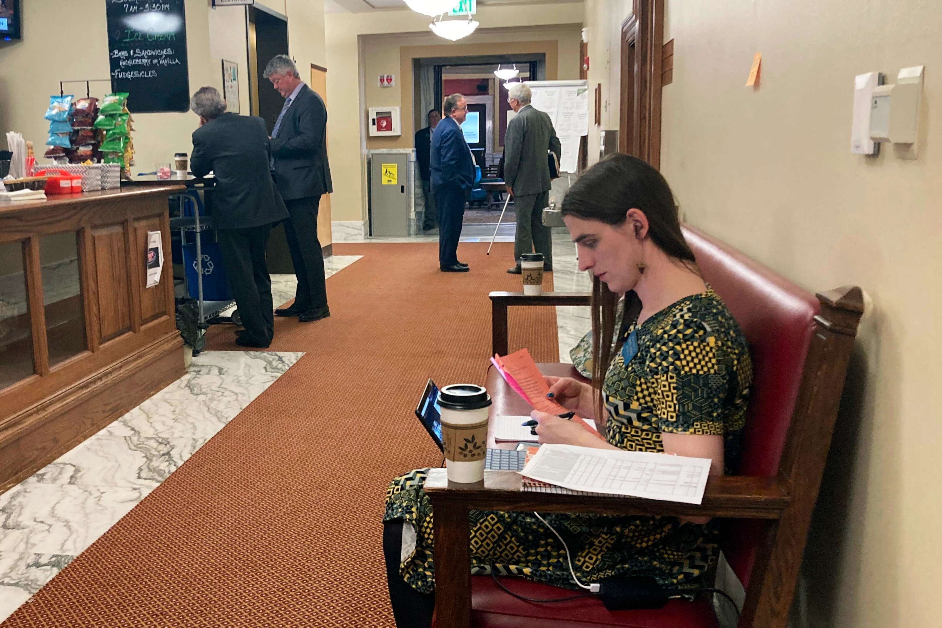 Zooey Zephyr works on a bench while her committee meets inside the House chamber.