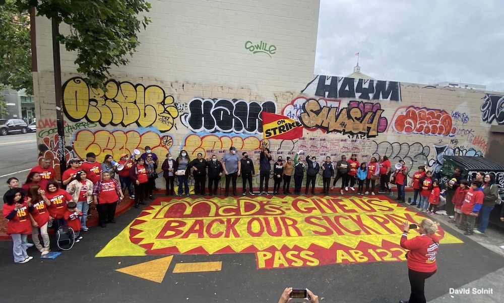 Photo of protesting McDonald's workers in a parking lot around a street mural: 