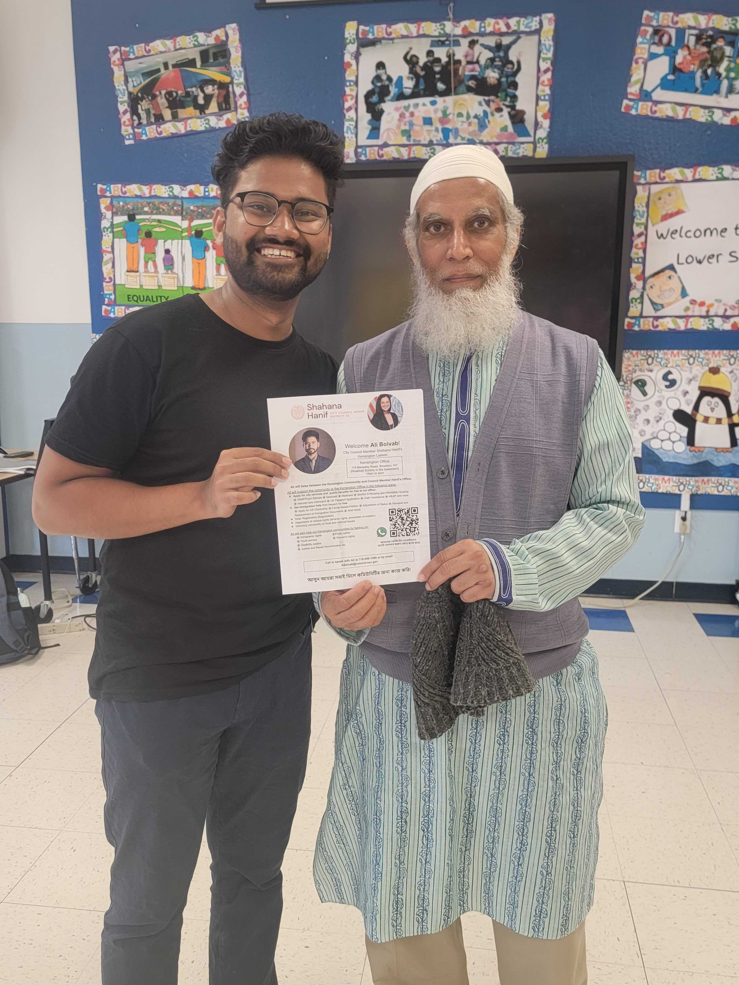 A picture of Ali and a constituent holding a flyer in a classroom.