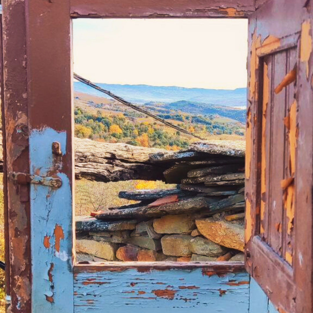 a photo of the pyrenees taken through the frame of a broken wooden window