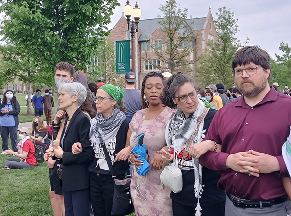 A photo of a human chain in front of the Washington University St. Louis encampment including Jill Stein, her Deputy Campaign manager wearing a green bandana on her head and a keffiyeh around her neck, and her campaign manager Jason Call wearing a burgundy button down shirt and gray slacks. In between Kelly and Jason are two St. Louis Board of Aldermen members, Alisha Sommier and President of the board, Megan Green, who joined with Jill’s team in the attempt to de-escalate with administration.