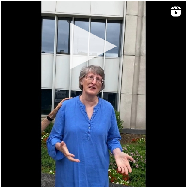 A still frame from a video shows a sad woman in a blue shirt in front of the FERC building