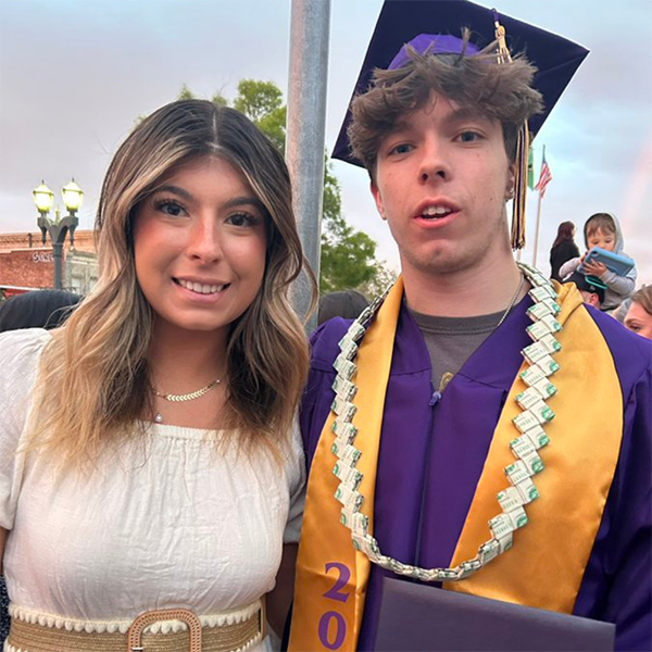 A photo of Jason’s daughter and son. Jason’s son, Trey, is wearing a purple graduation robe and cap with a gold drape.