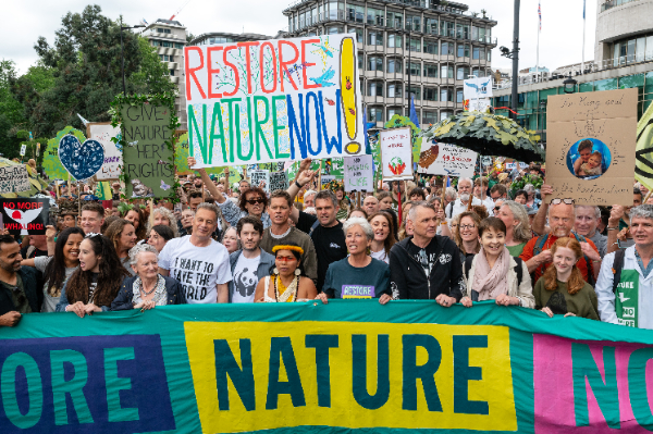 A photo of the front of the march, with various celebrities among those holding the Restore Nature Now banner