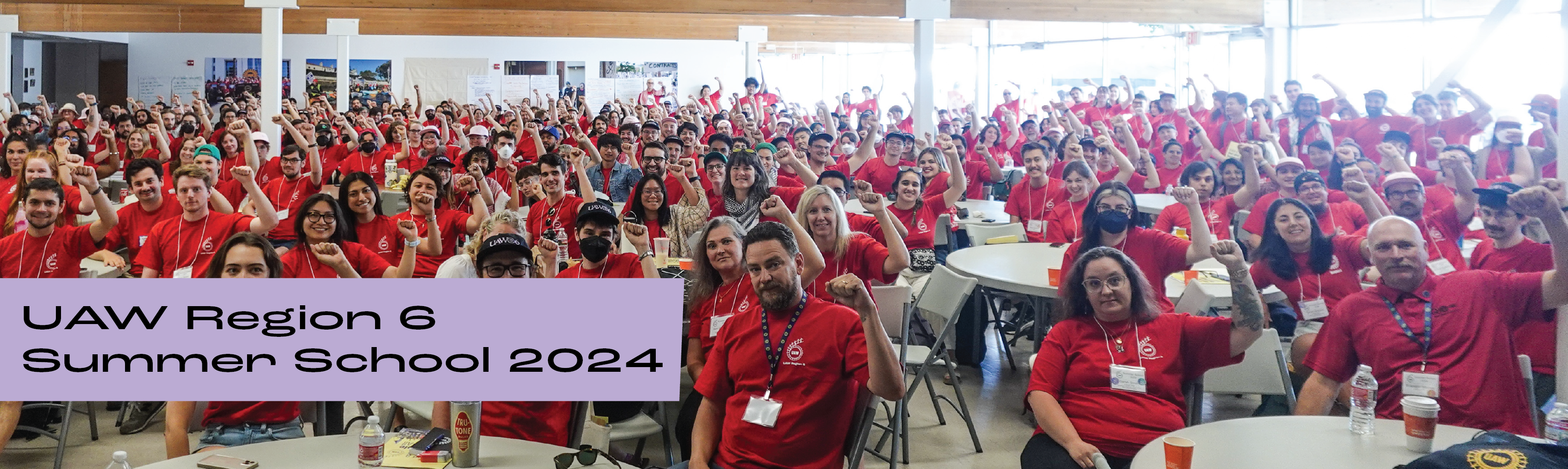 400 UAW region 6 members wearing red shirts and holding up raised fists in a large meeting hall