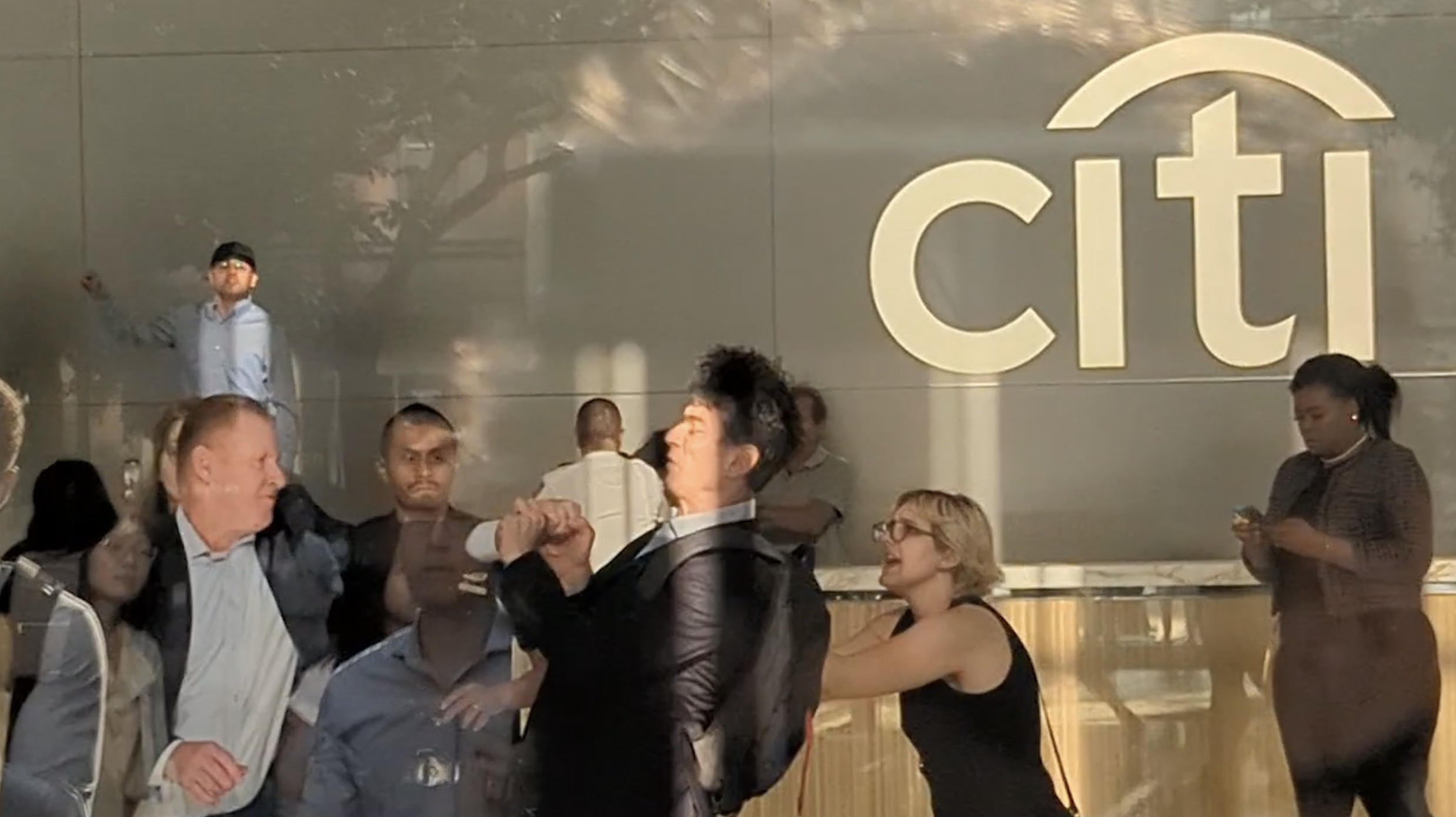 Citi staff punching a protestor in front of a citi logo