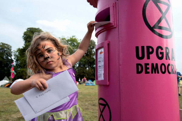 Young child with face painted posting a letter to the King in the pink letterbox