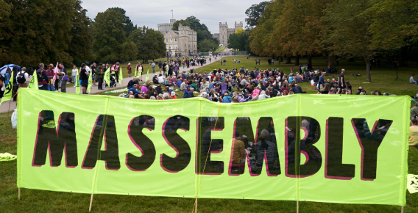 On the Long Walk in front of Windsor Castle, people sit on the grass in small groups taking part in a community assembly.