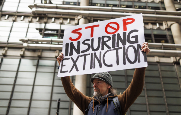 Man in front of Lloyd Building in London with placard reading 