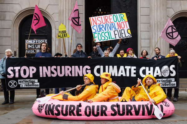 stop insuring climate chaos banner and pink inflatable liferaft with 3 oarsmen