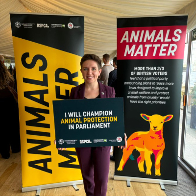 Carla Denyer holding a sign saying 'I will champion animal protection in parliament'.