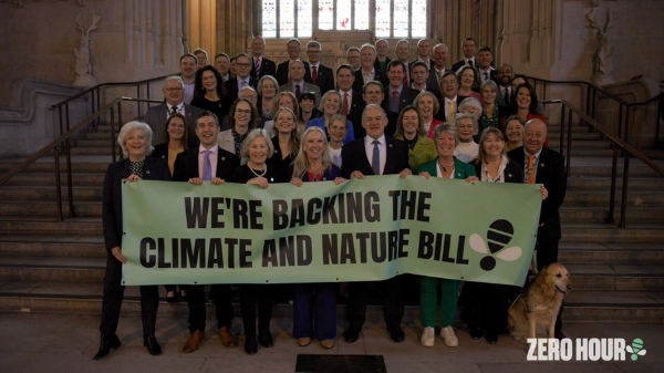 Green MPs at the steps of parliament with other campaigners holding a signs saying 'we're backing the climate and nature bill'.