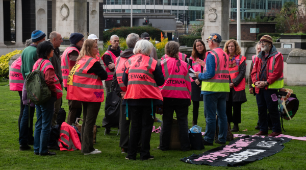 Volunteer stewards gather for briefing in a park before the action starts