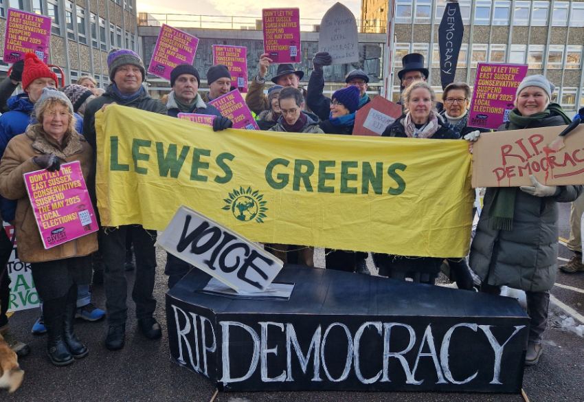  Lewes Greens protest at plans to merge district and county councils holding 'Lews Greens' and 'Rip democracy' signs.