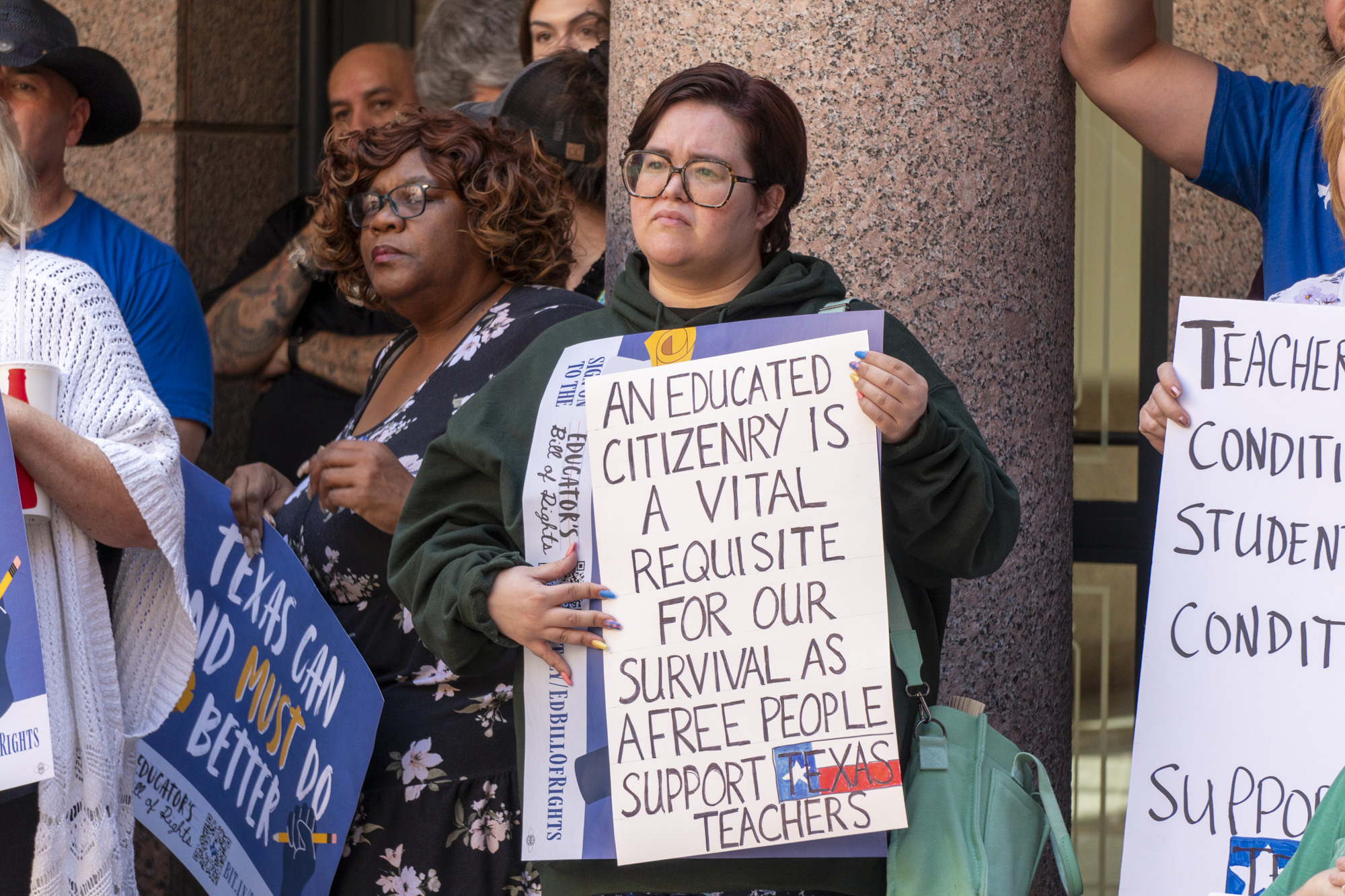 A public education supporter holds a sign during a rally at the capitol