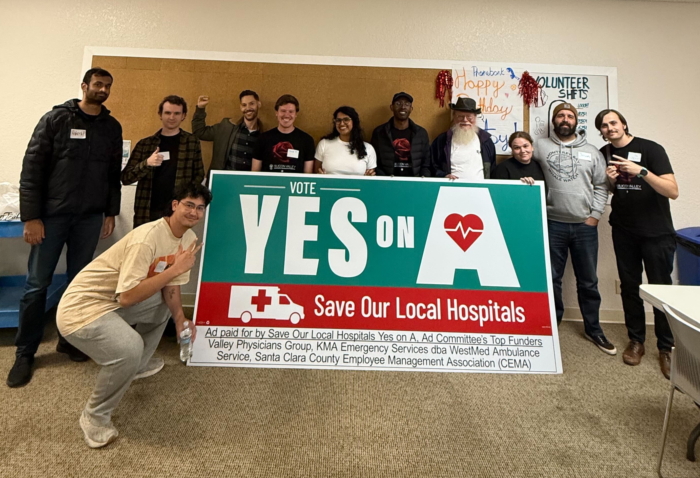 DSA members stand behind a large Vote Yes on A Save our Local Hospitals sign.