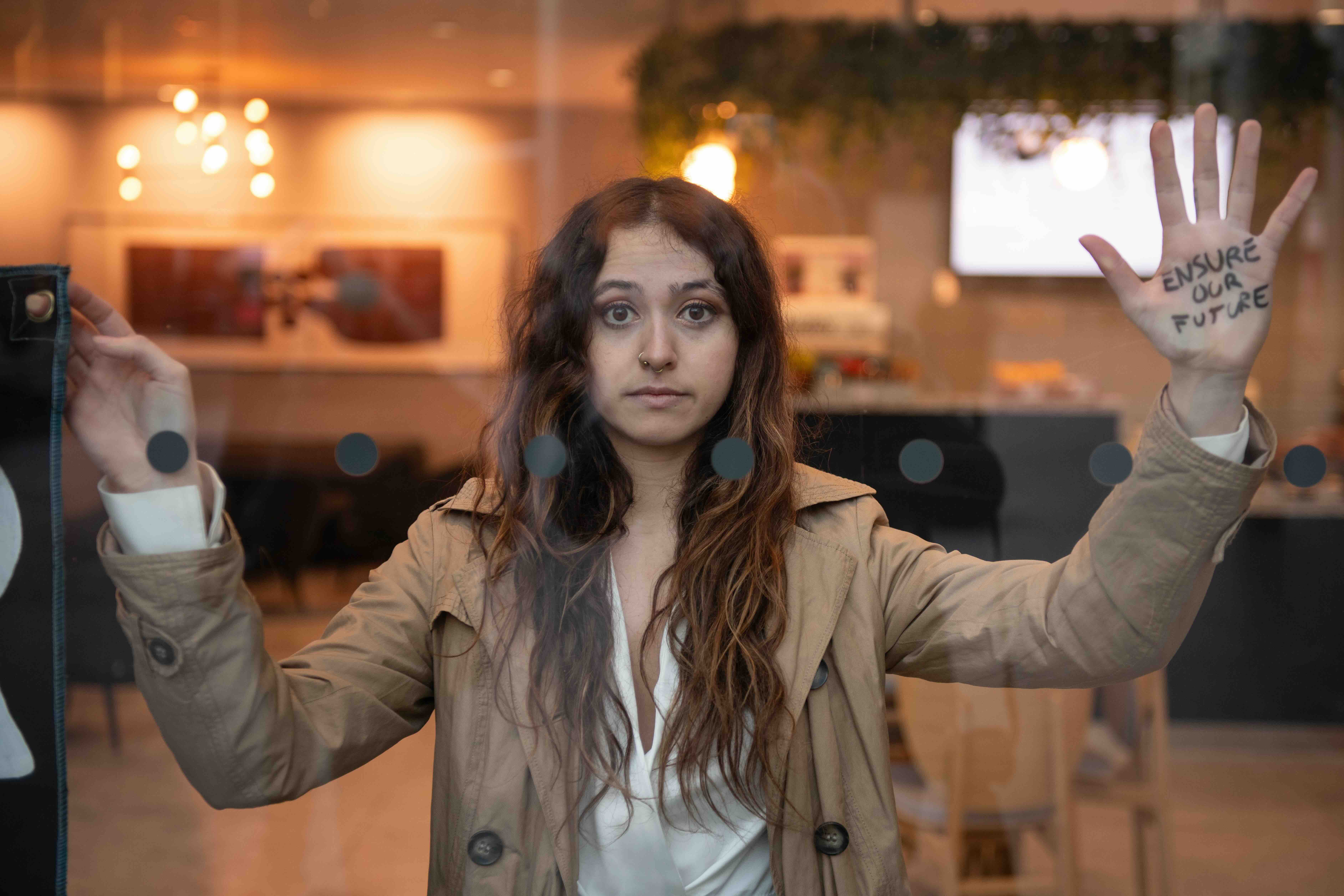 Woman behind window with ensure our survival written on her hand