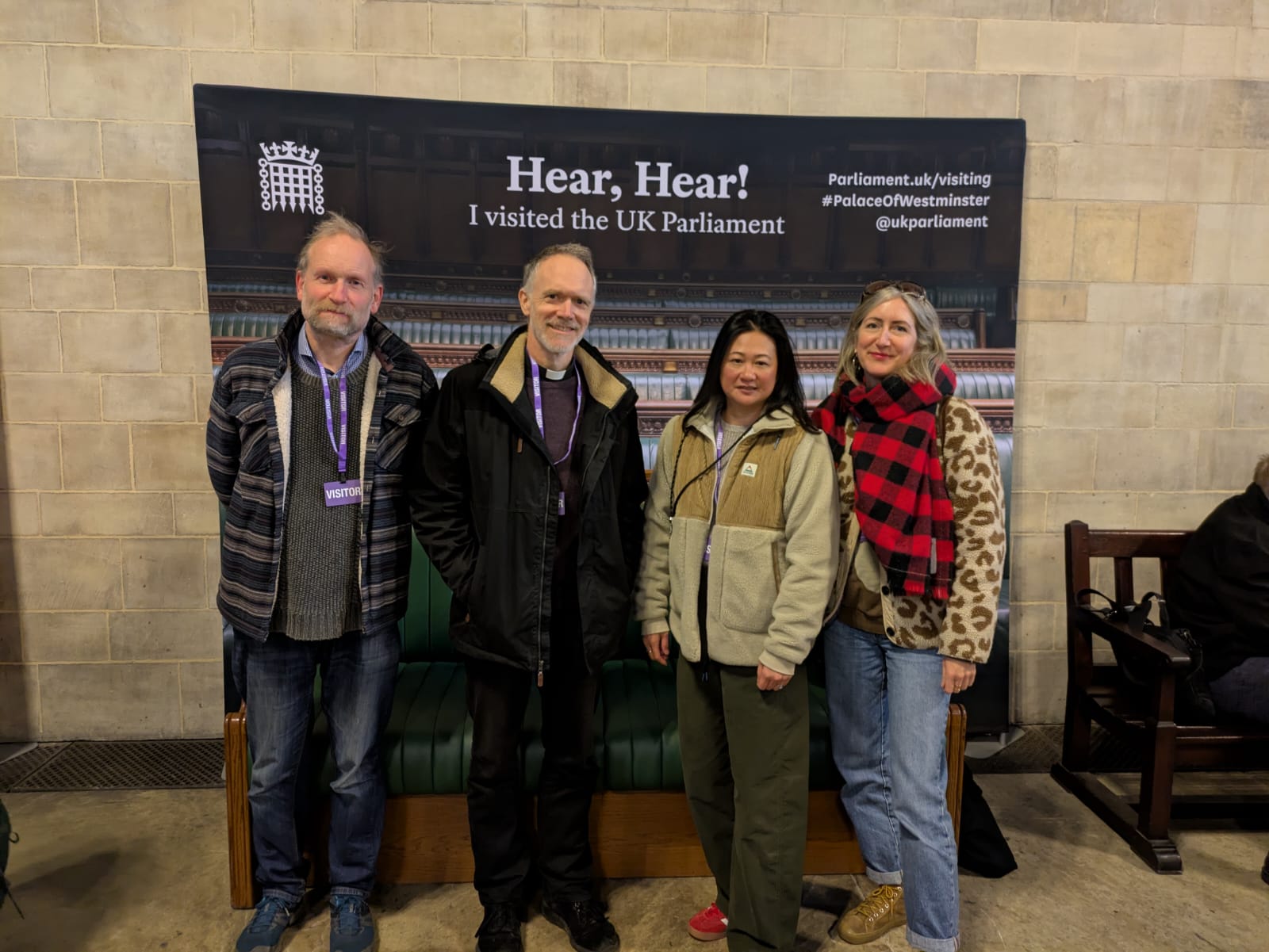 [Four people posed standing in front of large display saying 'I visited the UK Parliament']