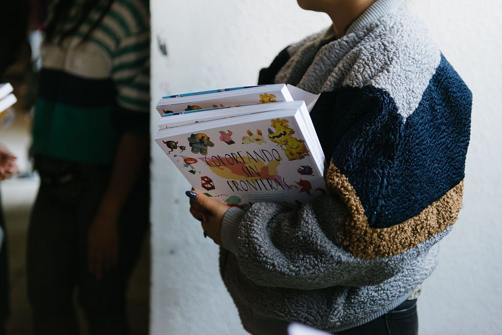 Adult holding a small stack of Coloring Without Borders books
