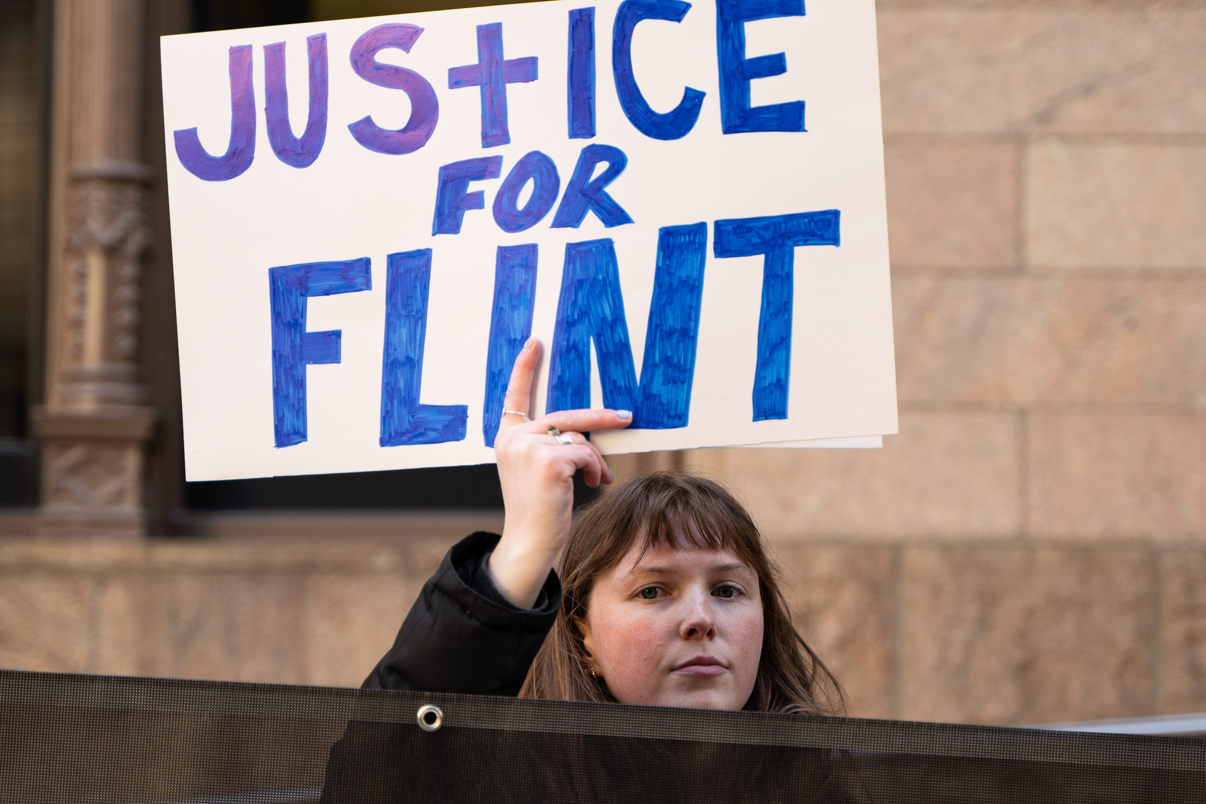 A protestor holding a sign that says "Justice for Flint" at a rally against Veolia