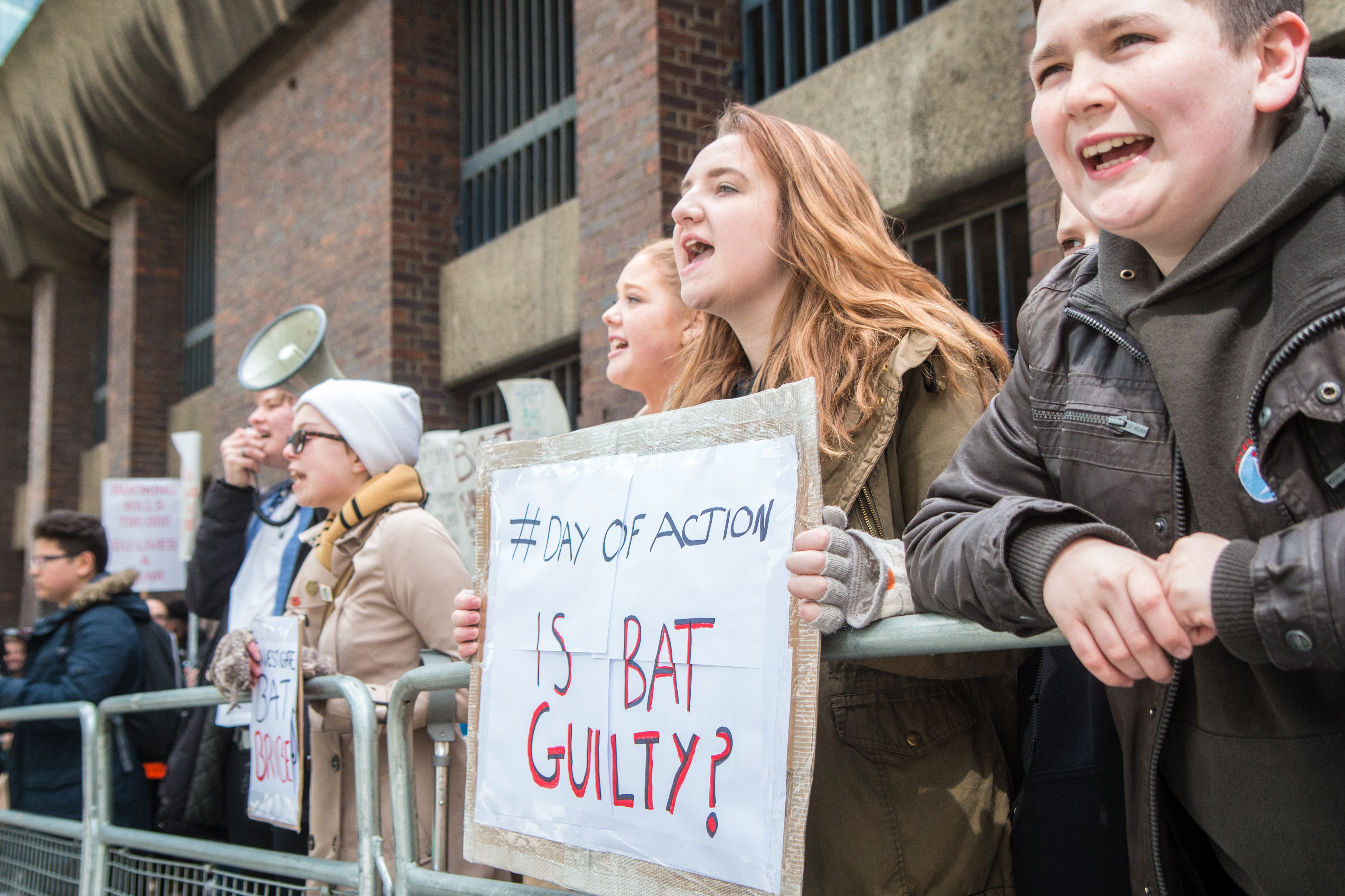 Protester at the British American Tobacco annual meeting holding a sign that says "IS BAT GUILTY?"
