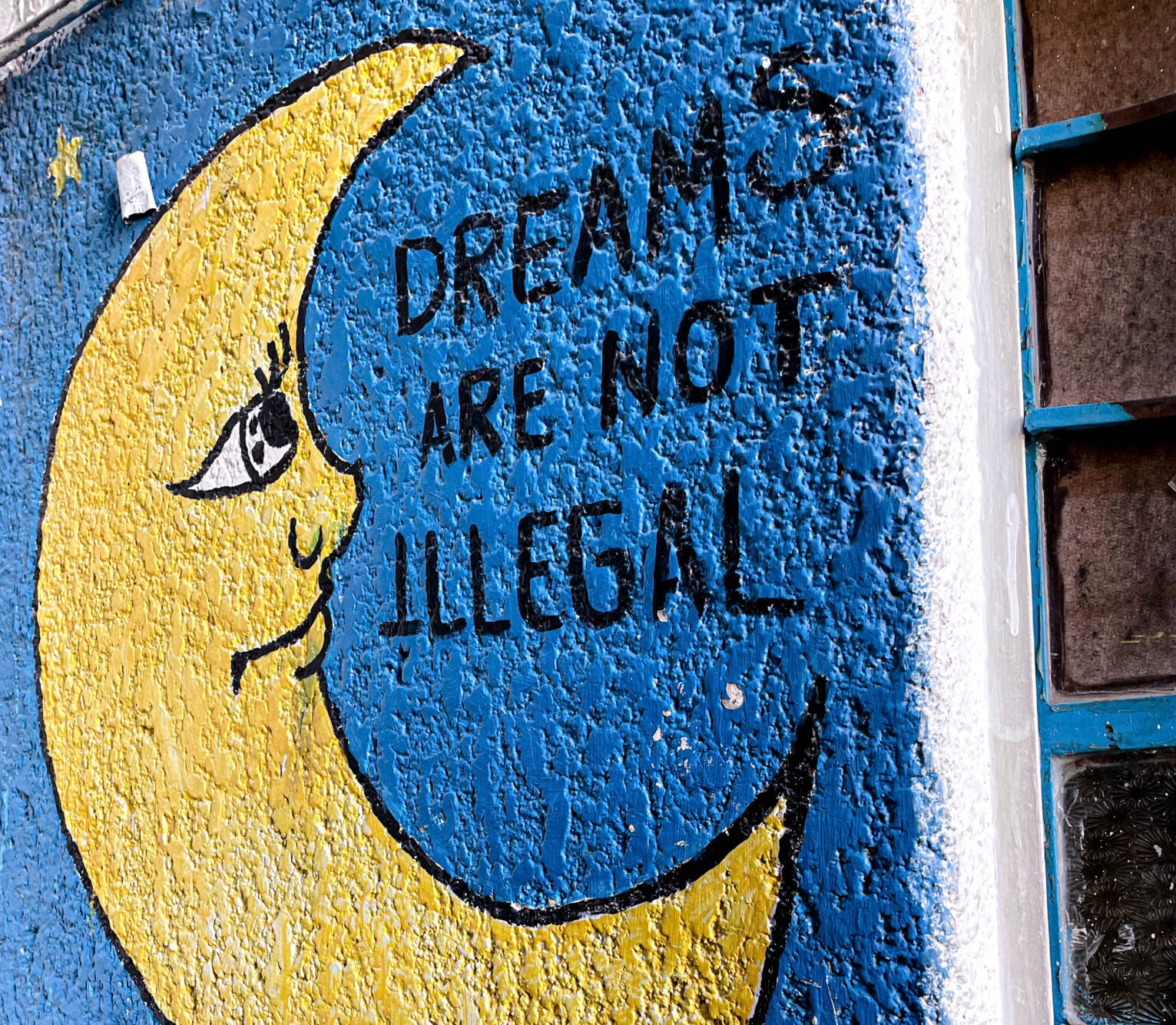 A painting of the moon with text DREAMS ARE NOT ILLEGAL